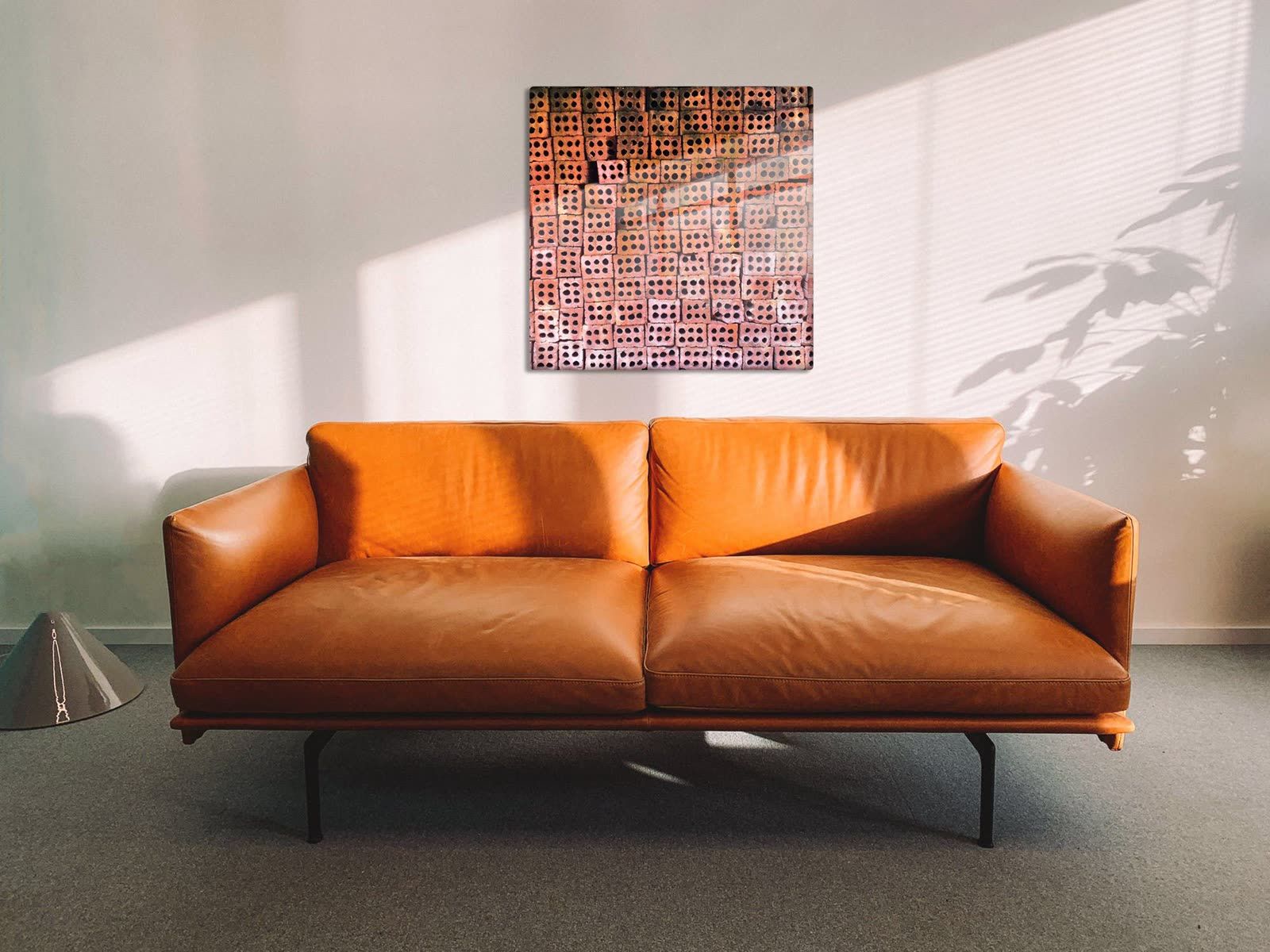 40 inch Patterns of Da Nang metal print centered above a cognac leather sofa